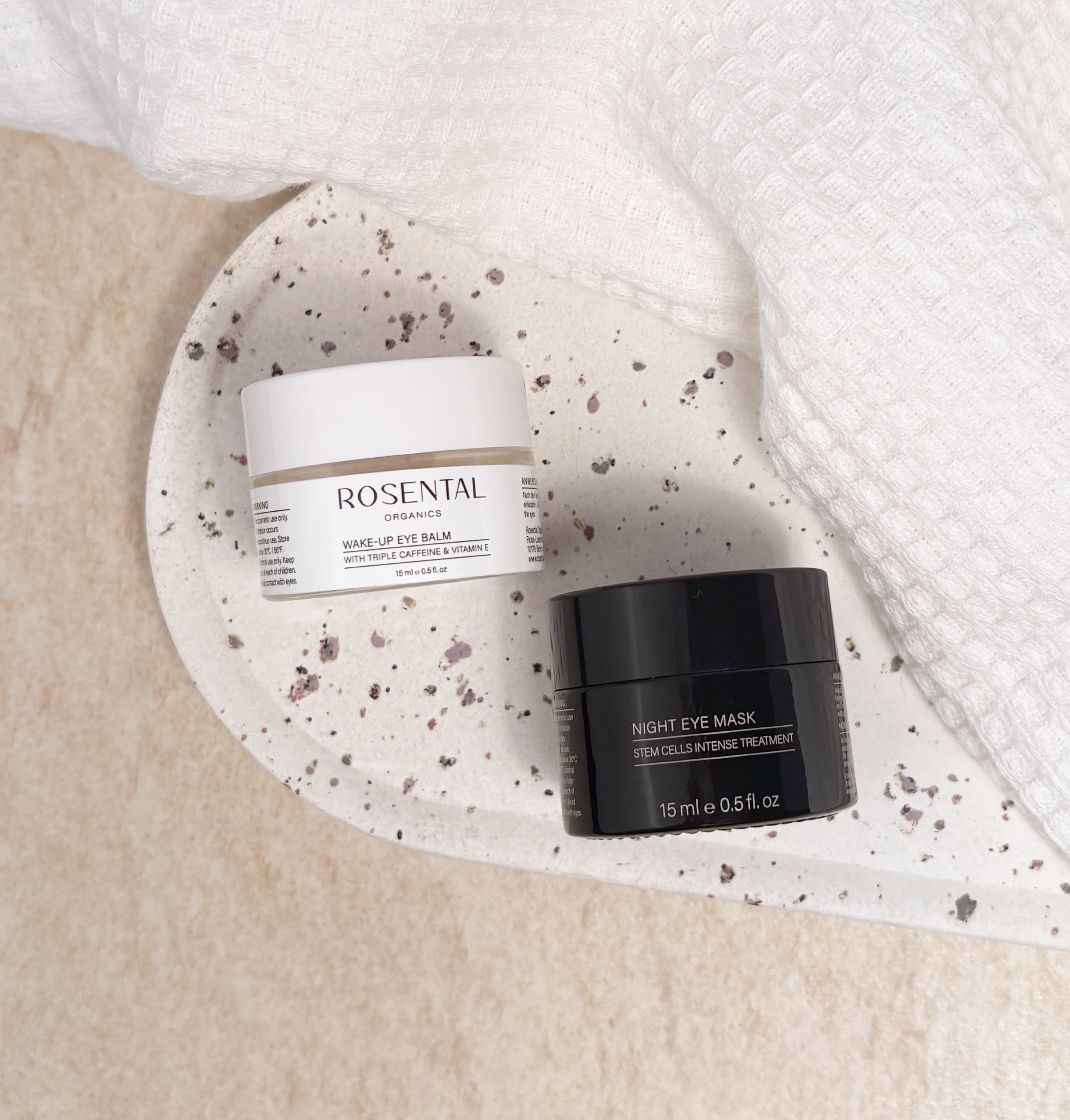 Witte en zwarte roompotten op een gebloemd bord, omgeven door een handdoek, op een lichte achtergrond.