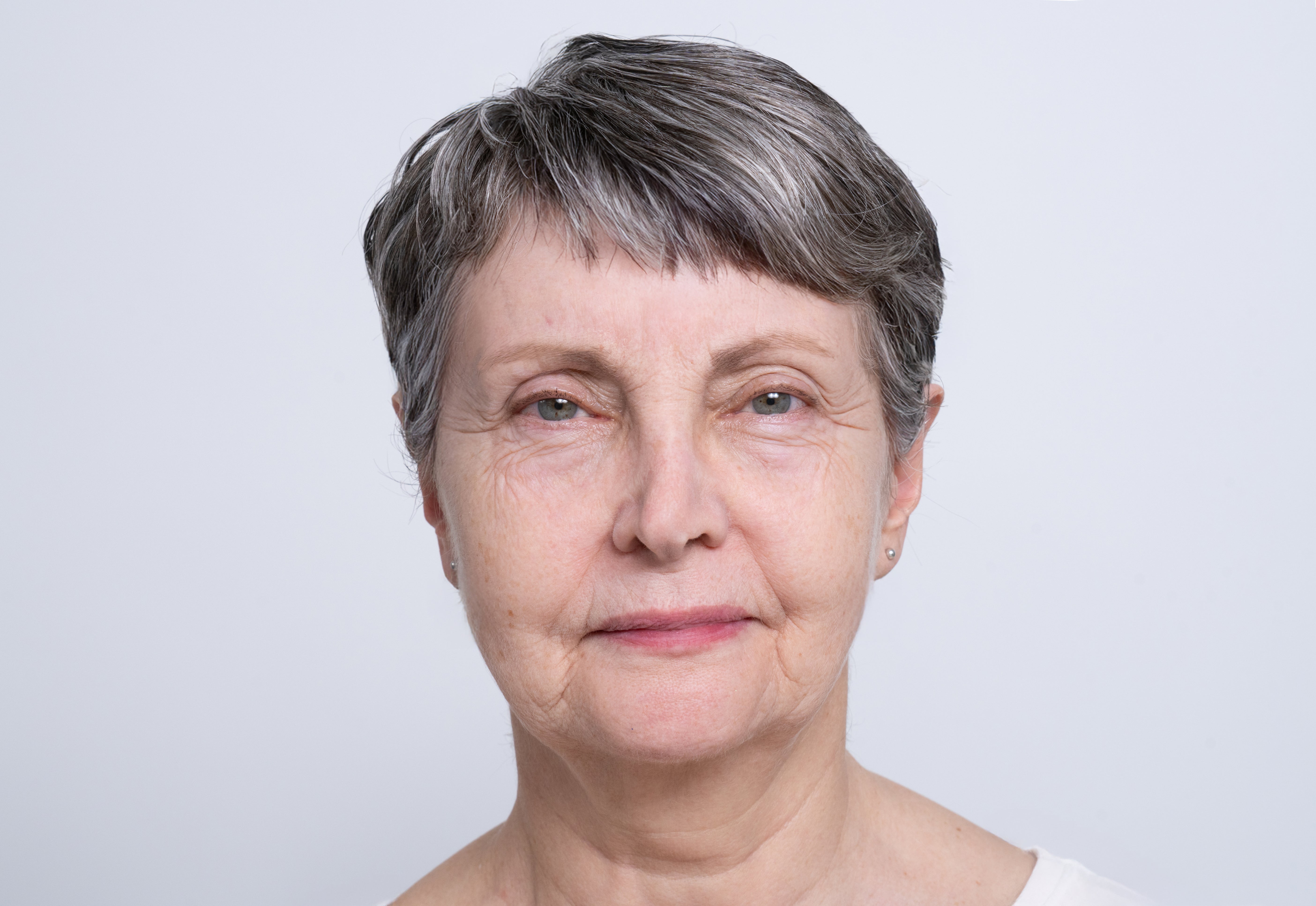 Portret van een oudere vrouw met grijs haar en zichtbaar verouderde huid.