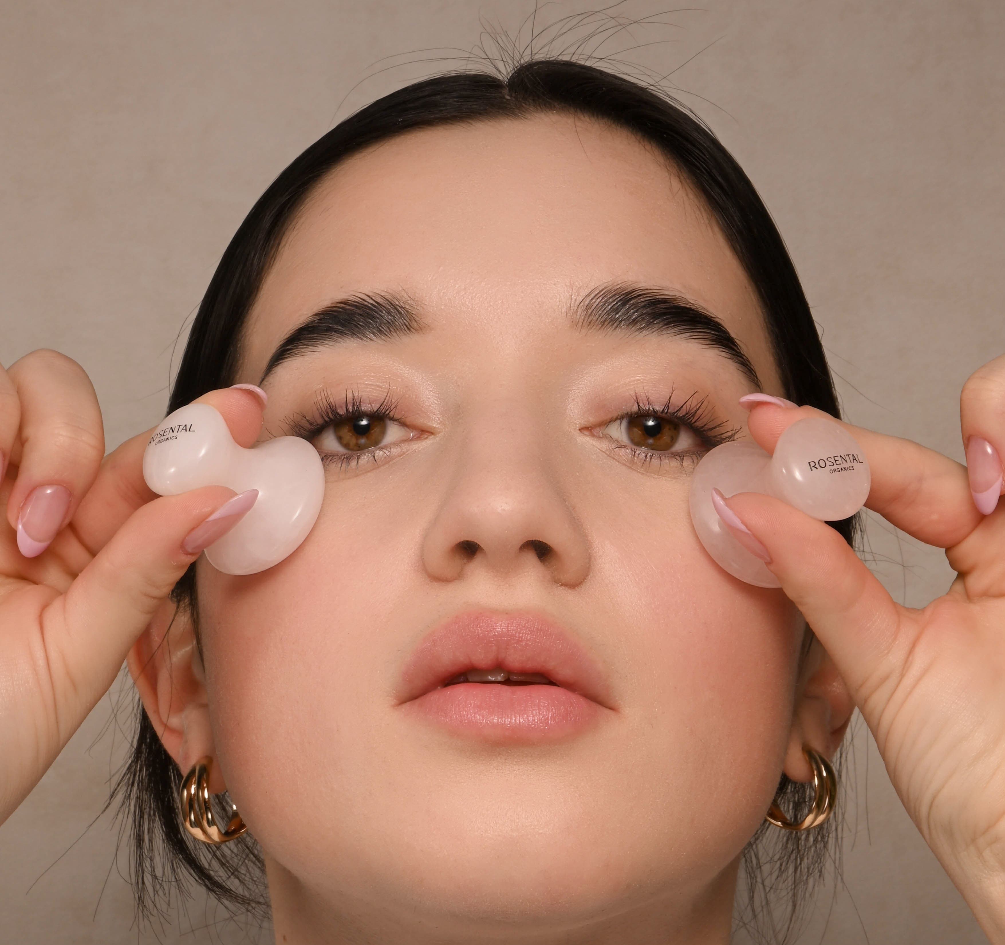 Een vrouw brengt het Full Face & Eye Yoga Set van Rosental Organics aan op beide wangen.